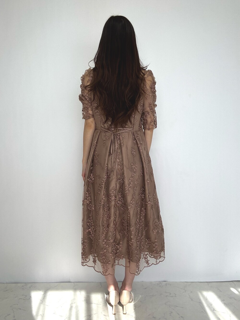 ベージュ系のクラッチバッグ、ブラウン系のドレスを着用したレディースの秋コーディネートの2枚目の写真