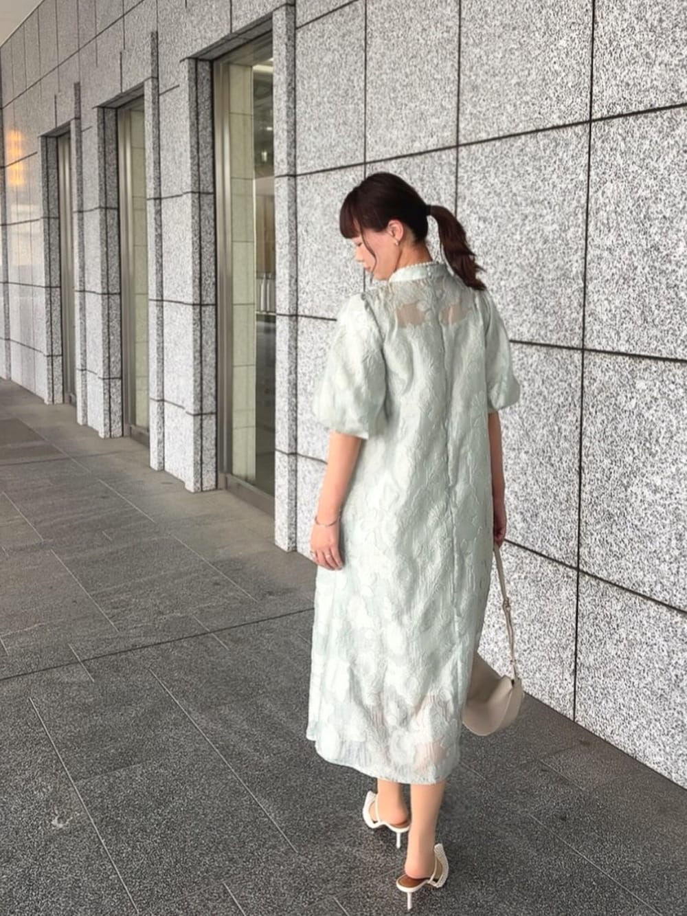 グリーン系のドレスを着用したレディースの春コーディネートの3枚目の写真