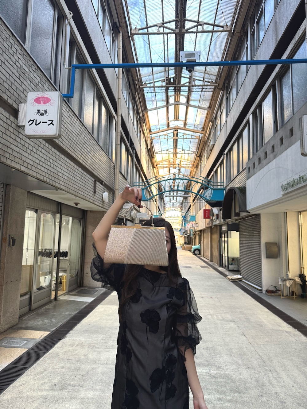 ブラック系のドレス、ブラック系のパンプス、ベージュ系のクラッチバッグを着用したレディースの秋コーディネートの3枚目の写真