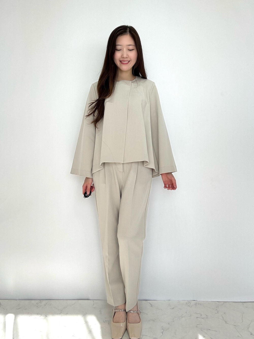 ベージュ系のスーツセットを着用したレディースの冬コーディネートの2枚目の写真