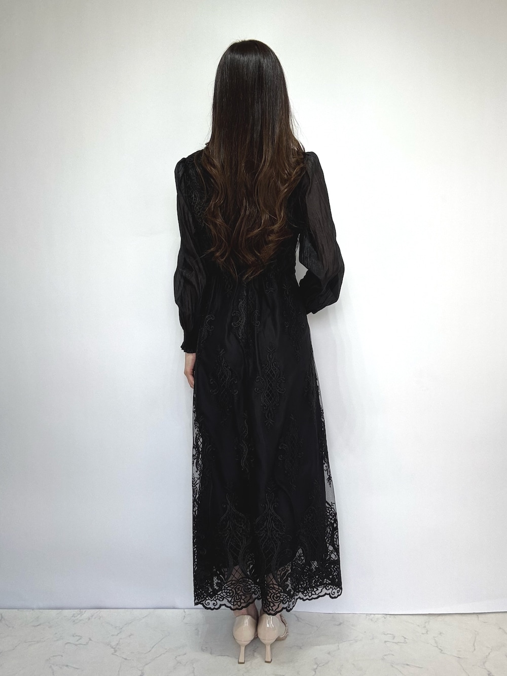 ベージュ系のクラッチバッグ、ベージュ系のパンプス、ブラック系のドレスを着用したレディースの秋コーディネートの4枚目の写真