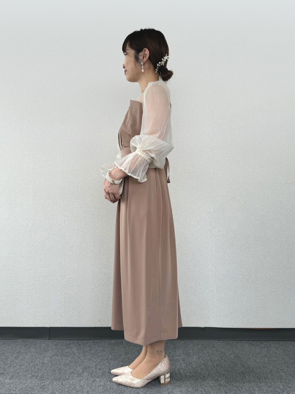 ブラウン系のドレス、ベージュ系のパンプス、ベージュ系のクラッチバッグを着用したレディースの冬コーディネートの2枚目の写真