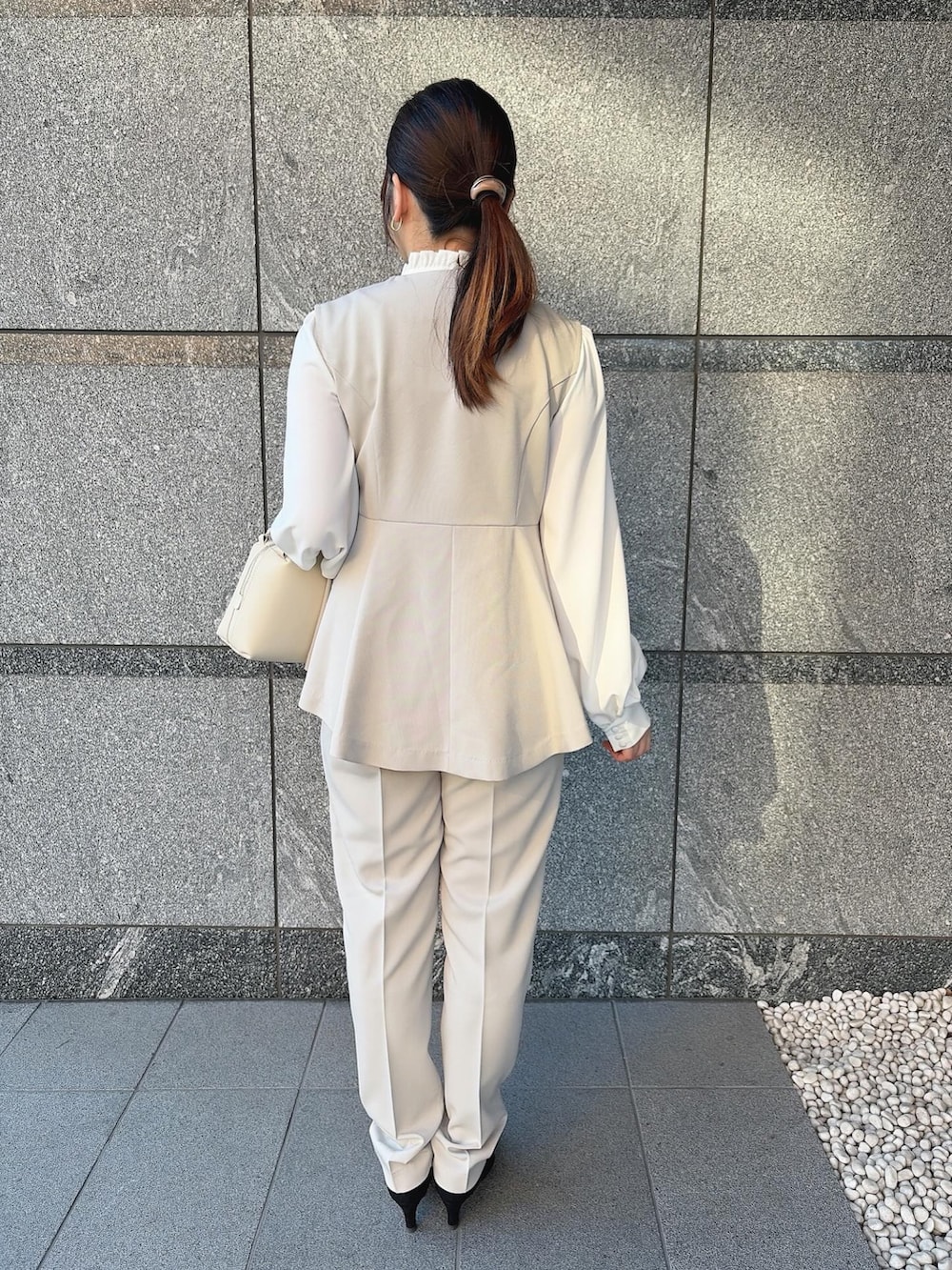 ベージュ系のスーツセットを着用したレディースの冬コーディネートの2枚目の写真