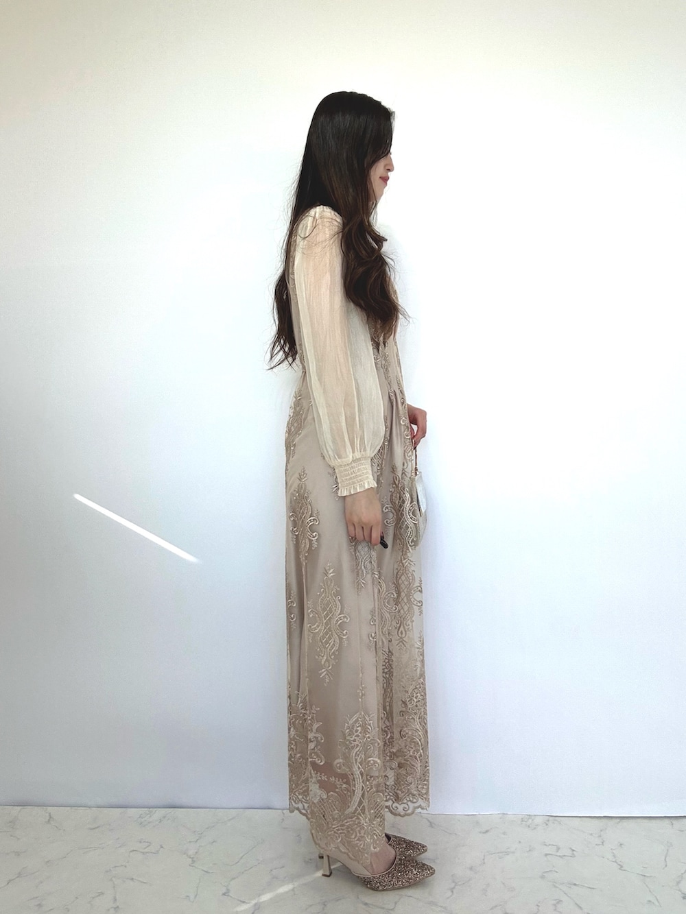 ベージュ系のドレス、ベージュ系のクラッチバッグ、ベージュ系のパンプスを着用したレディースの秋コーディネートの4枚目の写真