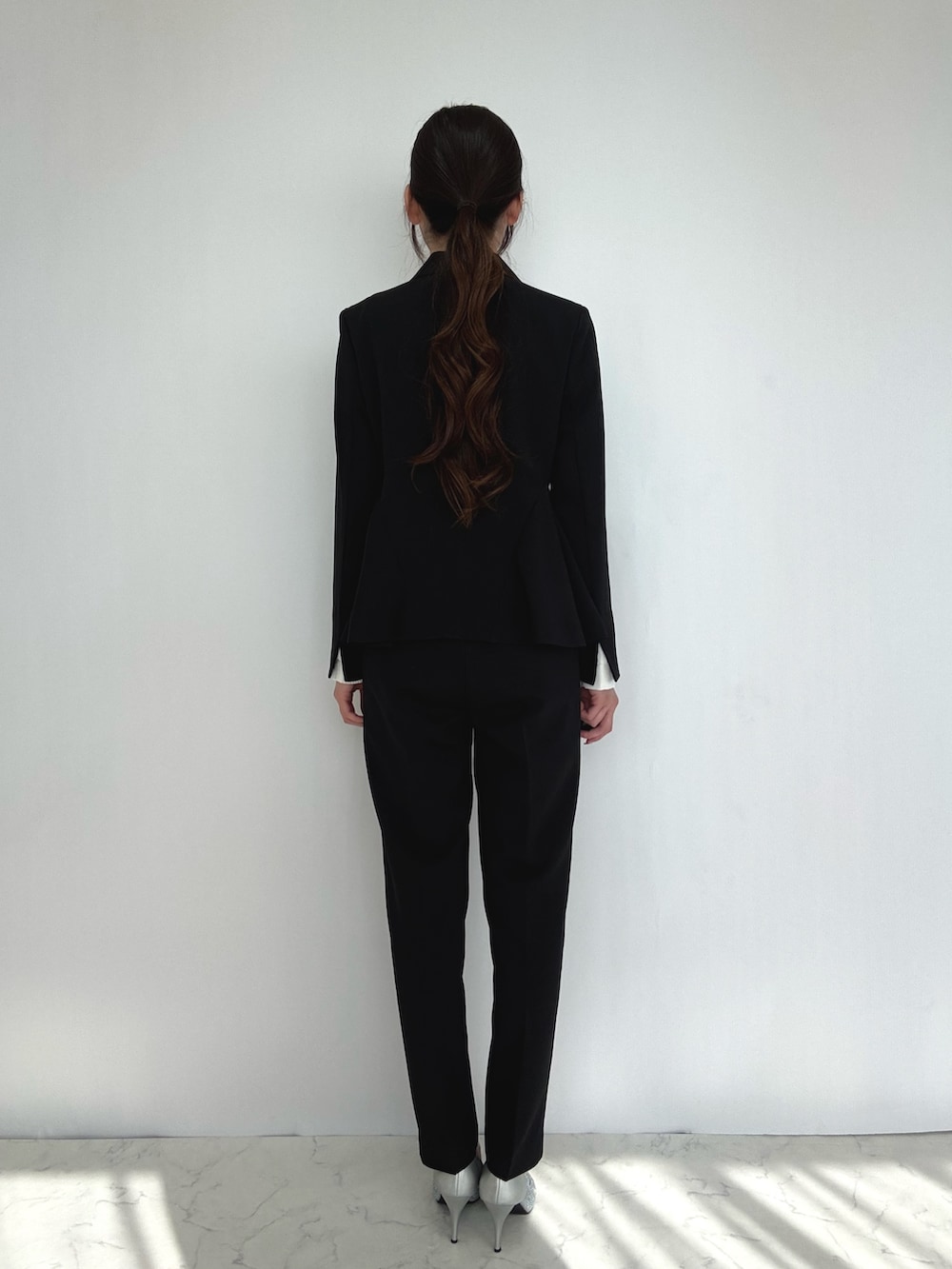 ブラック系のスーツセット、シルバー系のパンプスを着用したレディースの冬コーディネートの2枚目の写真