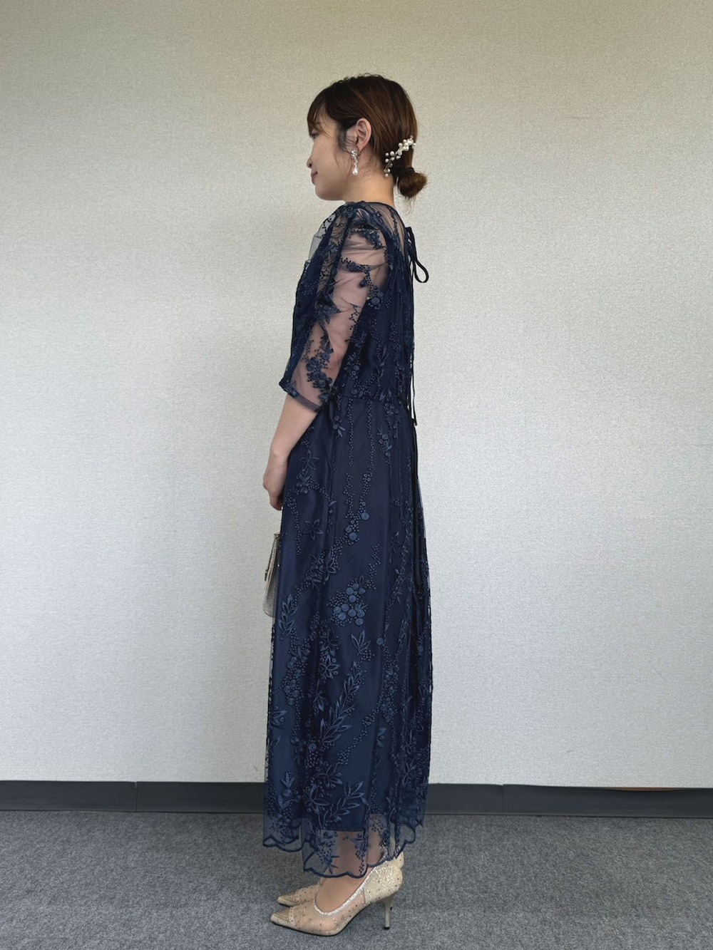 ブルー系のドレス、ベージュ系のクラッチバッグ、ゴールド系のパンプスを着用したレディースの冬コーディネートの2枚目の写真