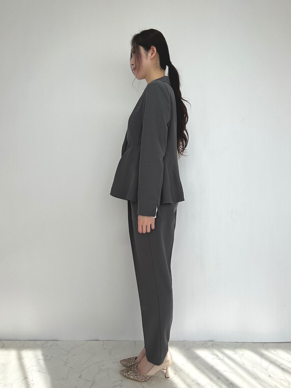 グレー系のスーツセット、ベージュ系のパンプスを着用したレディースの冬コーディネートの2枚目の写真