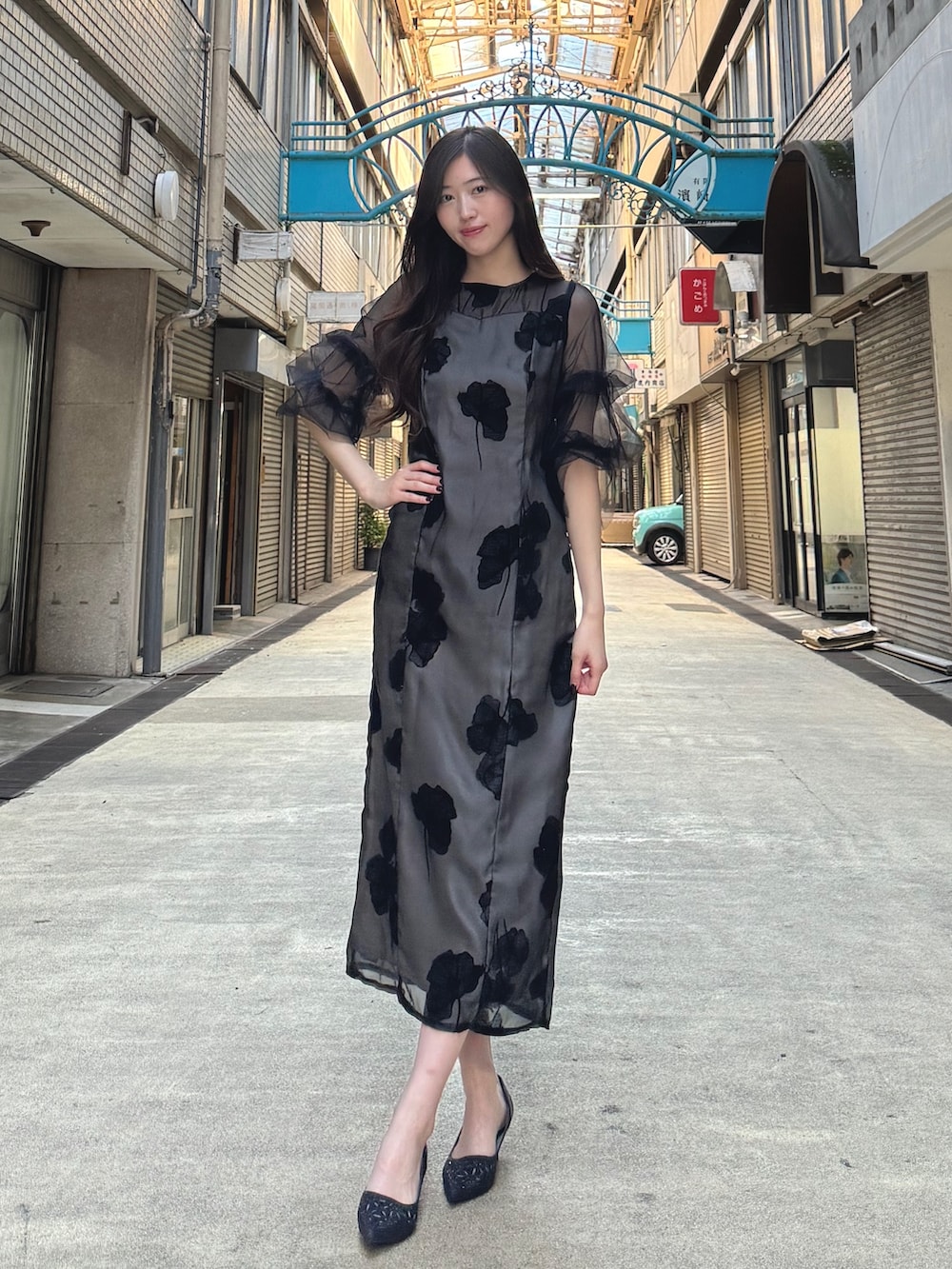 ブラック系のドレス、ブラック系のパンプス、ベージュ系のクラッチバッグを着用したレディースの秋コーディネートの5枚目の写真