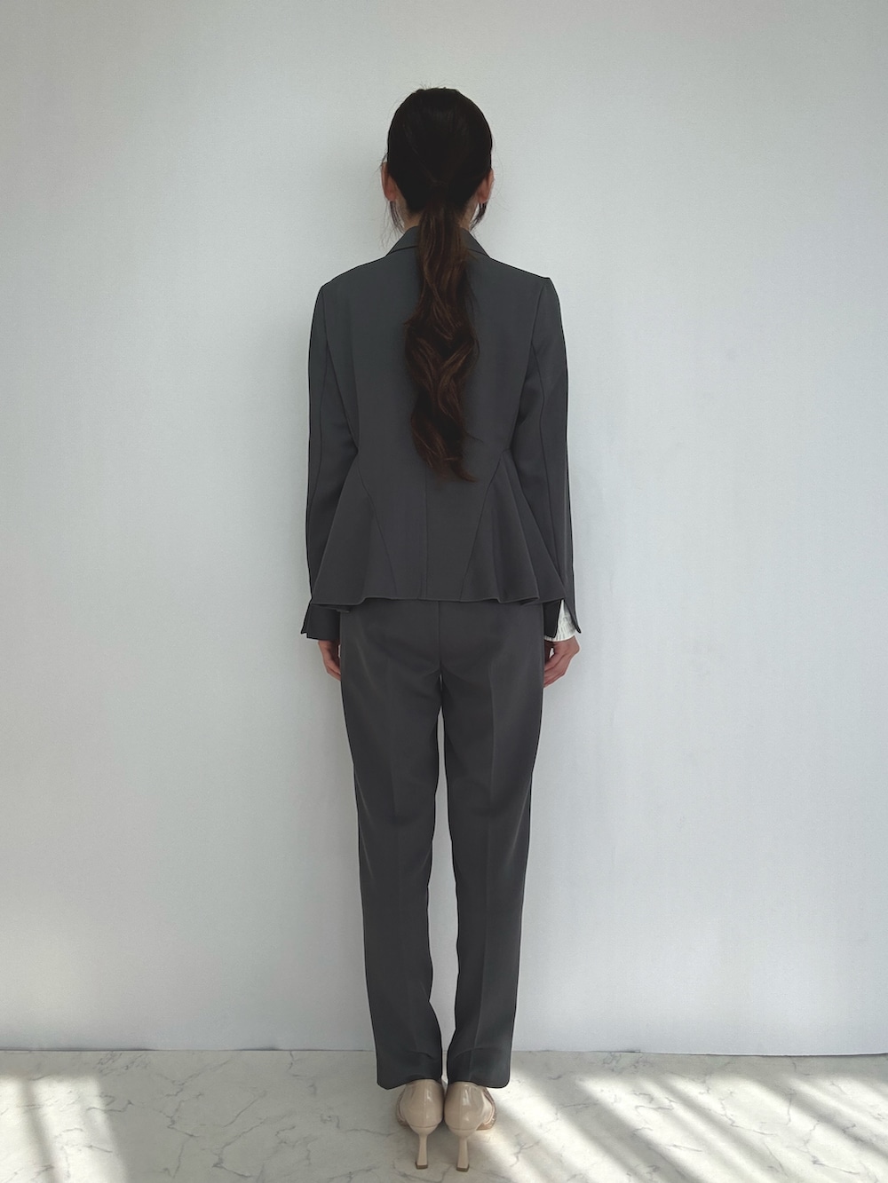 グレー系のスーツセット、ベージュ系のパンプスを着用したレディースの冬コーディネートの3枚目の写真