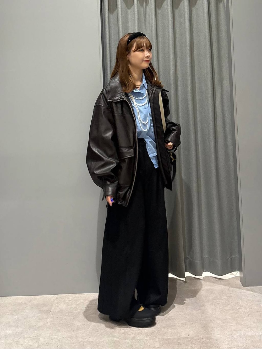 ブラック系のショルダーバッグ、ブルー系のシャツ/ブラウス、ブラウン系のブルゾンを着用したレディースの秋コーディネートの6枚目の写真