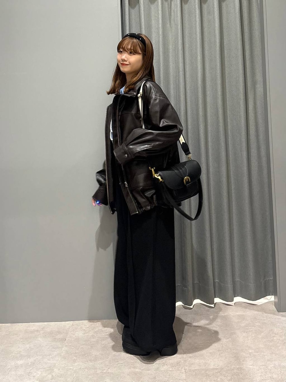 ブラック系のショルダーバッグ、ブルー系のシャツ/ブラウス、ブラウン系のブルゾンを着用したレディースの秋コーディネートの2枚目の写真