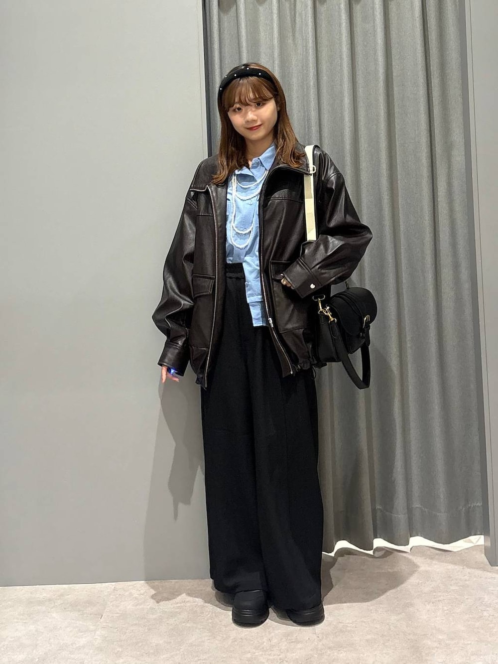 ブラック系のショルダーバッグ、ブルー系のシャツ/ブラウス、ブラウン系のブルゾンを着用したレディースの秋コーディネートの7枚目の写真