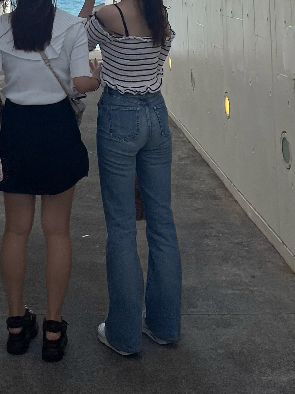 ブルー系のデニムパンツ、ホワイト系のスニーカー、ベージュ系のかごバッグを着用したレディースの秋コーディネートの3枚目の写真