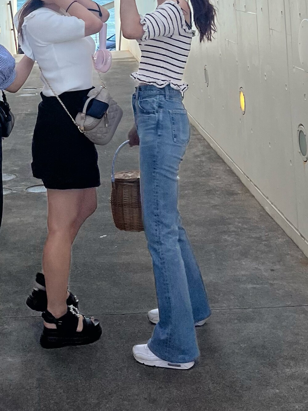 ブルー系のデニムパンツ、ホワイト系のスニーカー、ベージュ系のかごバッグを着用したレディースの秋コーディネートの2枚目の写真