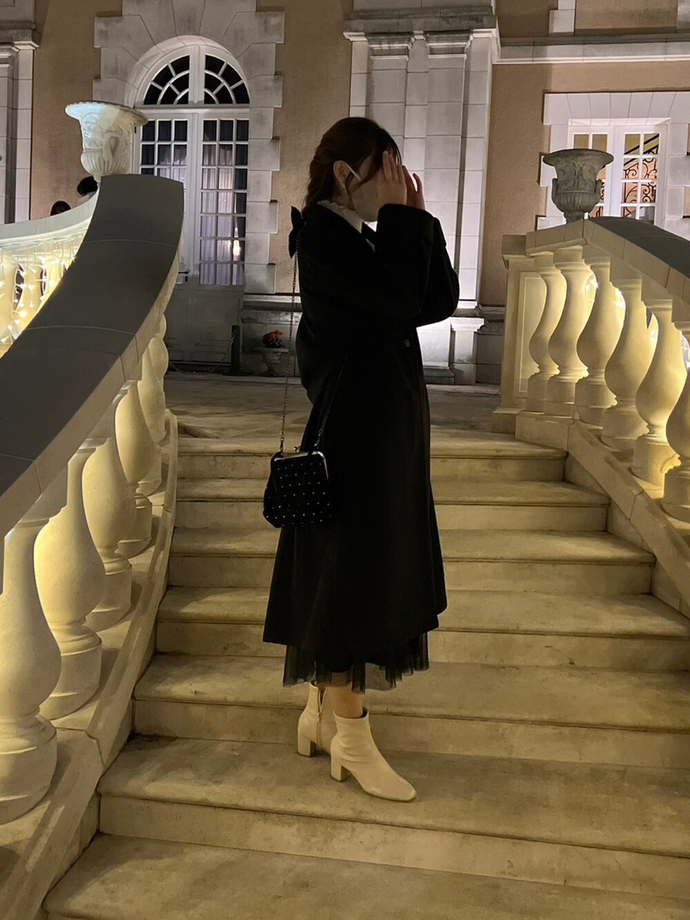 ブラック系のショルダーバッグ、ブラック系のステンカラーコート、ベージュ系のブーツを着用したレディースの秋コーディネートの2枚目の写真