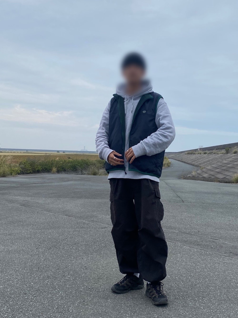 グレー系のパーカー、ブルー系のダウンベスト、ブラック系のカーゴパンツを着用したメンズの秋コーディネートの2枚目の写真