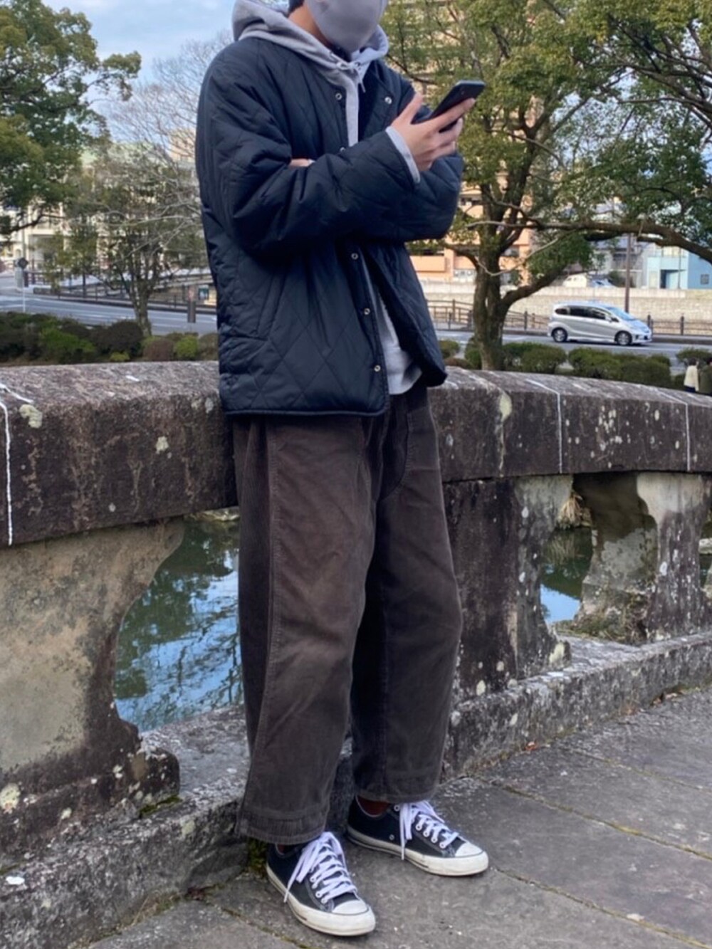 グレー系のパーカー、ブラック系のブルゾン、グリーン系のパンツを着用したメンズの冬コーディネートの2枚目の写真