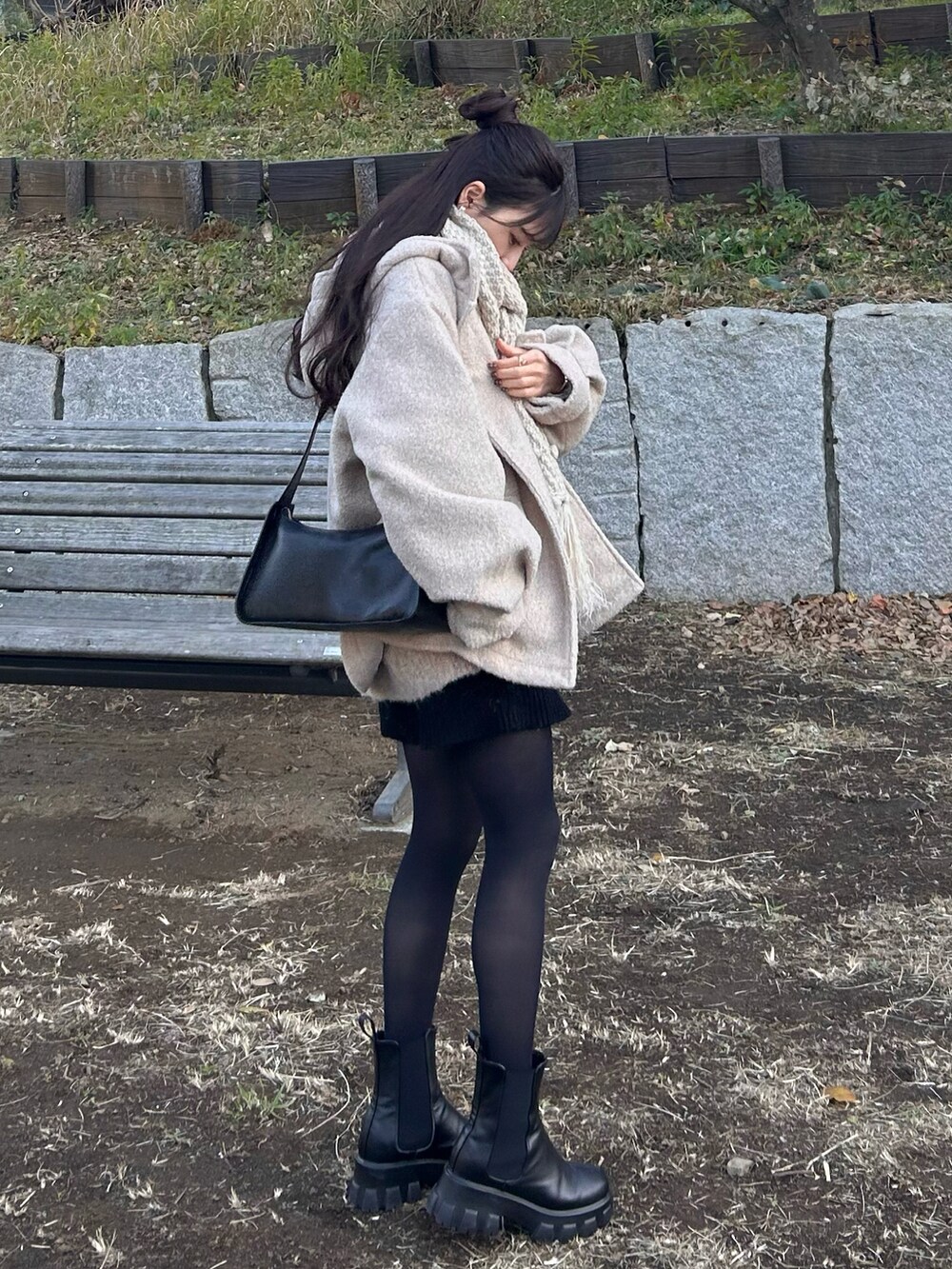 ホワイト系のダッフルコート、ブラック系のショルダーバッグ、ブラック系のブーツを着用したレディースの冬コーディネートの3枚目の写真