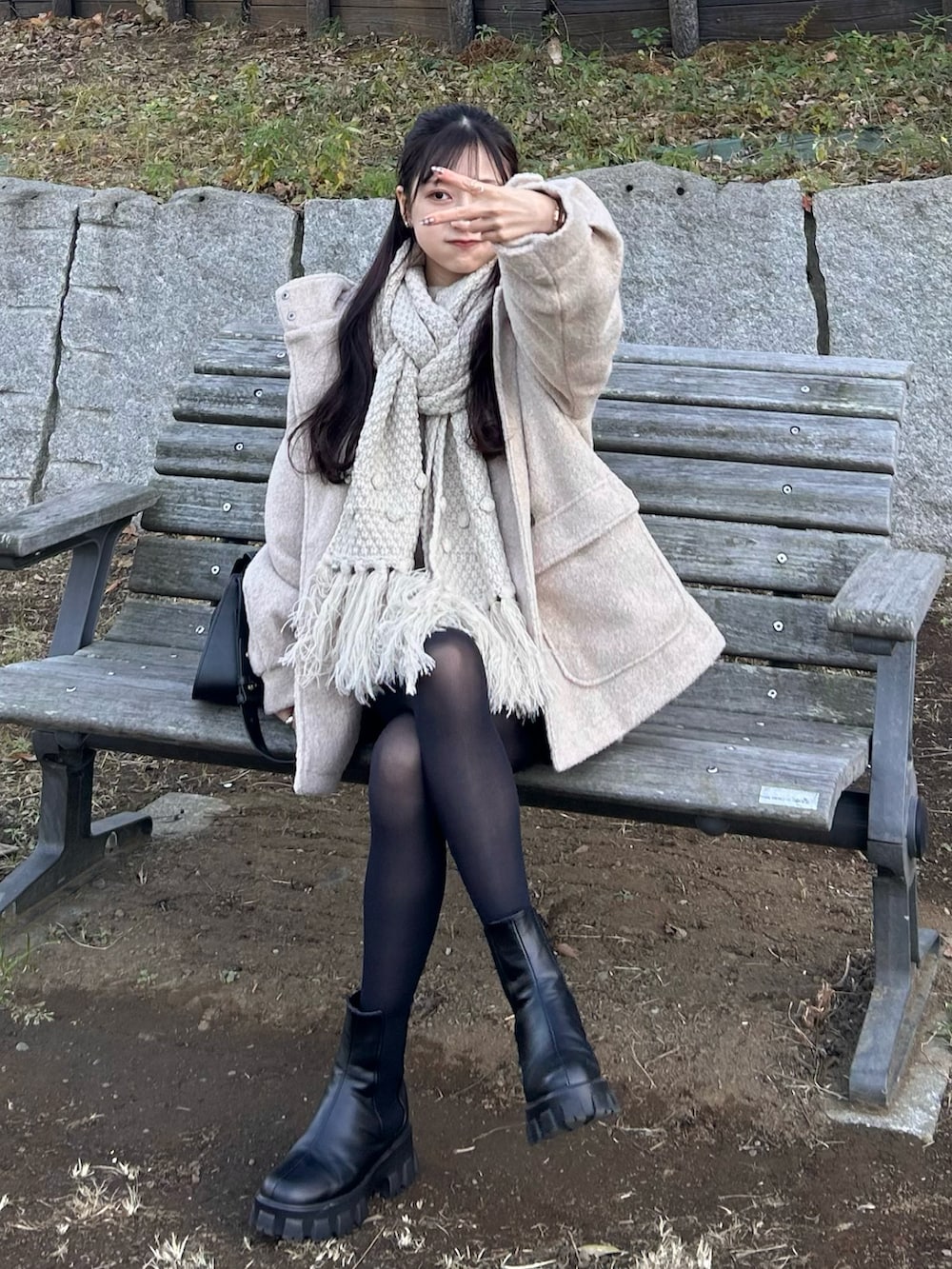 ホワイト系のダッフルコート、ブラック系のショルダーバッグ、ブラック系のブーツを着用したレディースの冬コーディネートの2枚目の写真