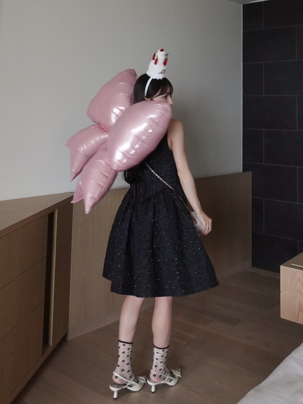 ホワイト系のパンプス、ホワイト系のハンドバッグ、ブラック系のドレスを着用したレディースの夏コーディネートの3枚目の写真