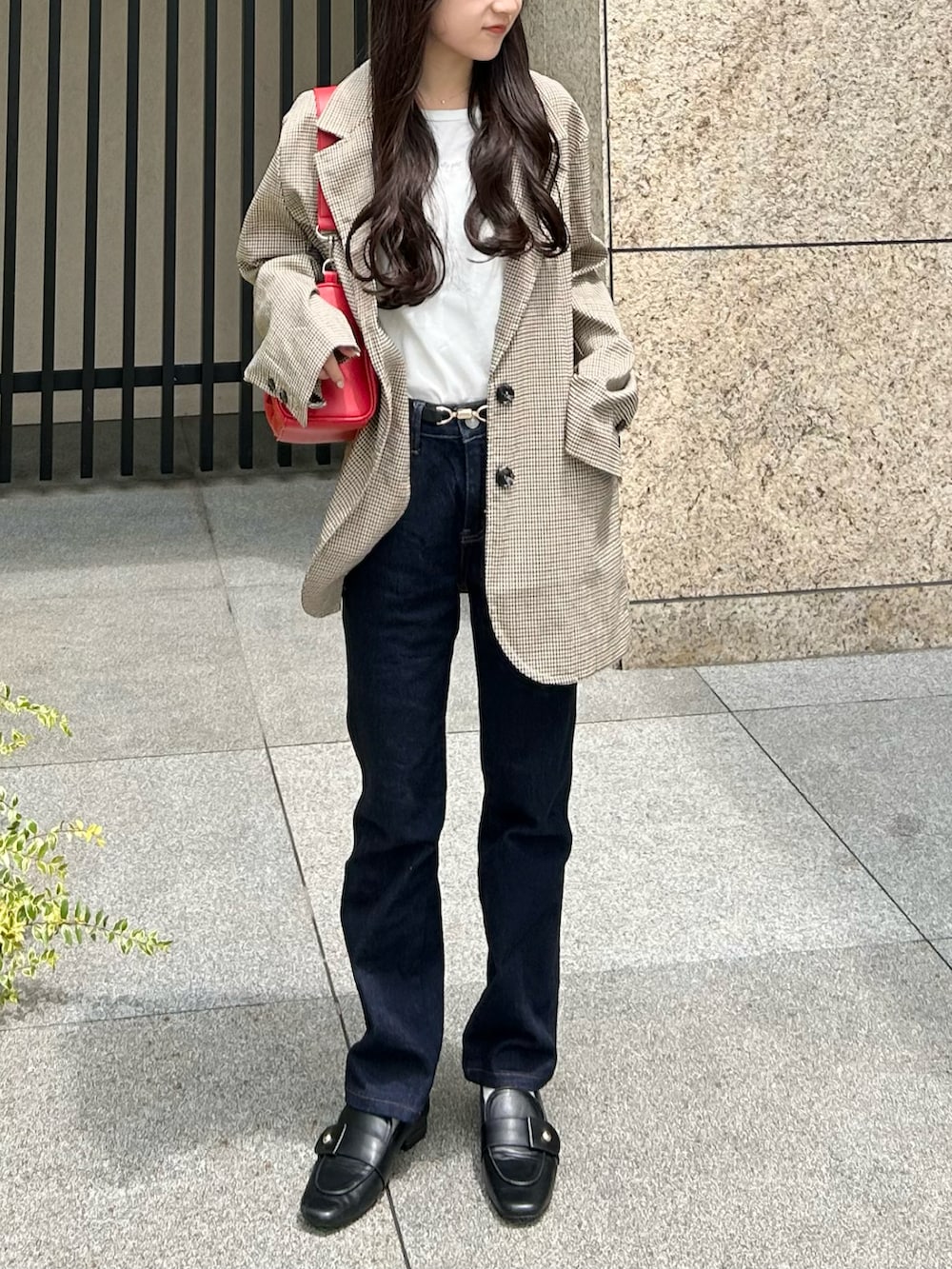 ブルー系のデニムパンツ、ベージュ系のテーラードジャケット、レッド系のショルダーバッグを着用したレディースの夏コーディネートの4枚目の写真