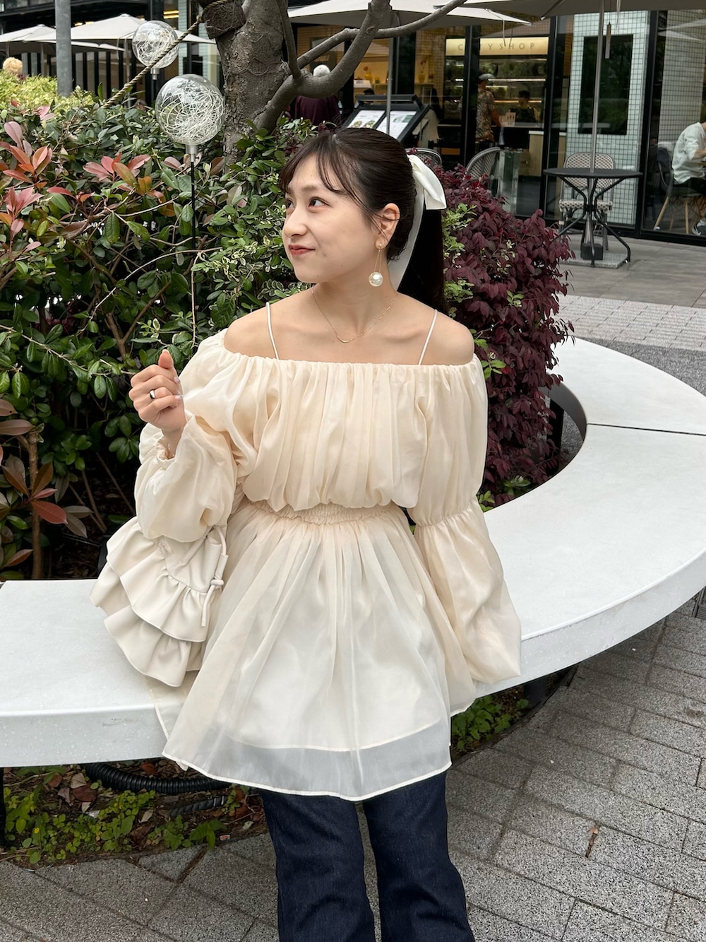 ブルー系のデニムパンツ、ホワイト系のトップス、ホワイト系のショルダーバッグを着用したレディースの春コーディネートの3枚目の写真