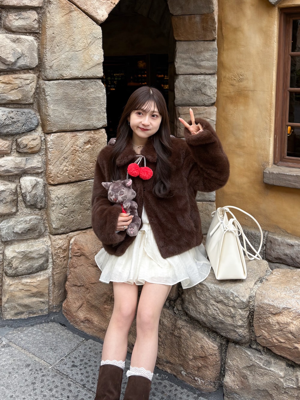 ブラウン系のブーツ、ホワイト系のワンピース、ブラウン系のジャケット/アウターを着用したレディースの春コーディネートの2枚目の写真