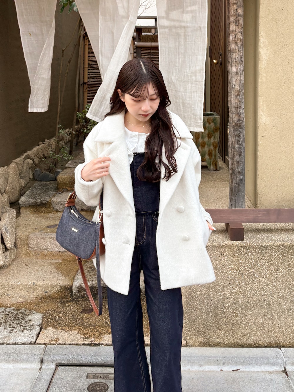 ホワイト系のジャケット/アウター、ブルー系のデニムパンツ、ブルー系のショルダーバッグを着用したレディースの春コーディネートの2枚目の写真