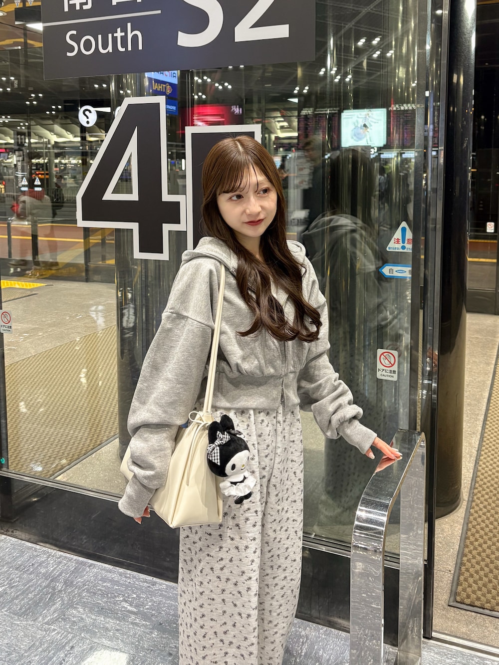 ホワイト系のブルゾン、グレー系のスウェットパンツ、ベージュ系のショルダーバッグを着用したレディースの春コーディネートの3枚目の写真