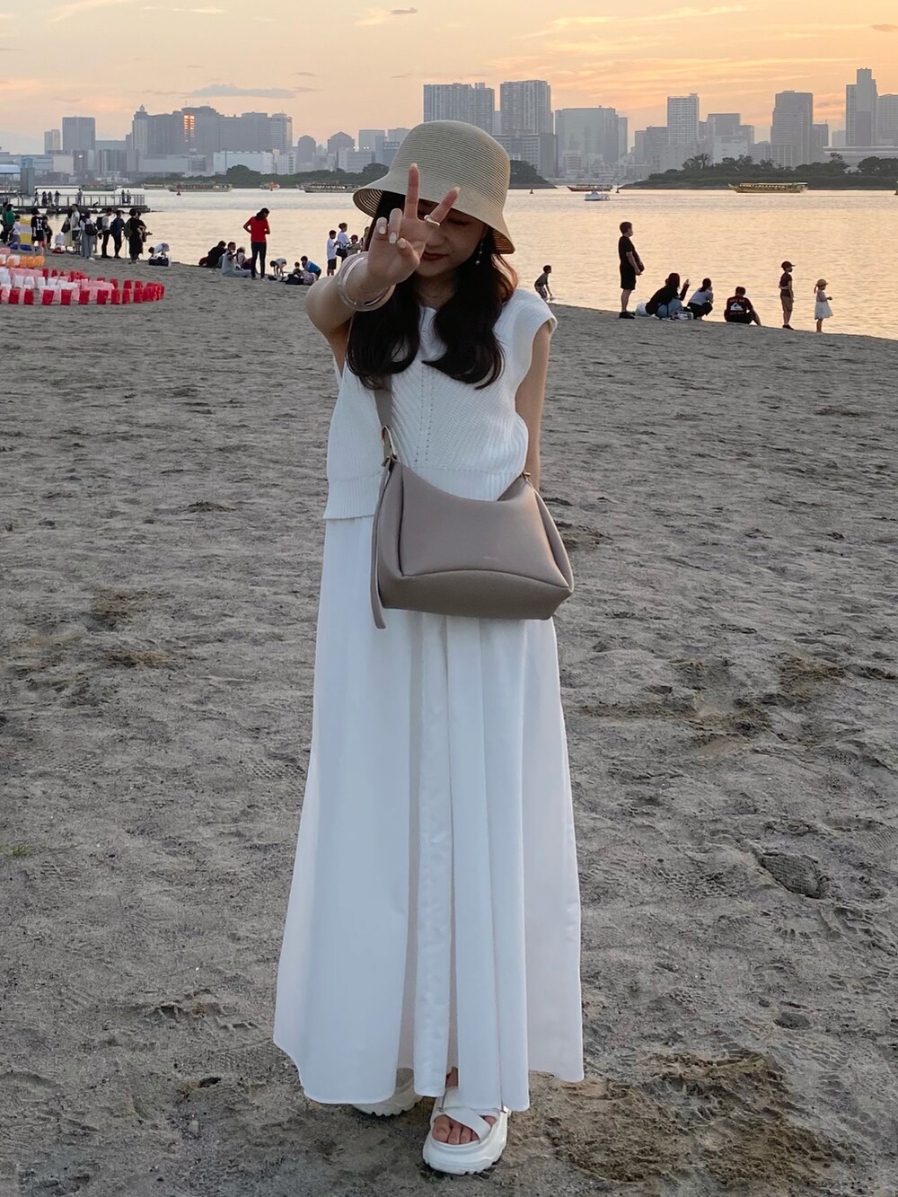 ベージュ系のバッグ、ホワイト系のワンピース、ホワイト系のサンダルを着用したレディースの夏コーディネートの2枚目の写真