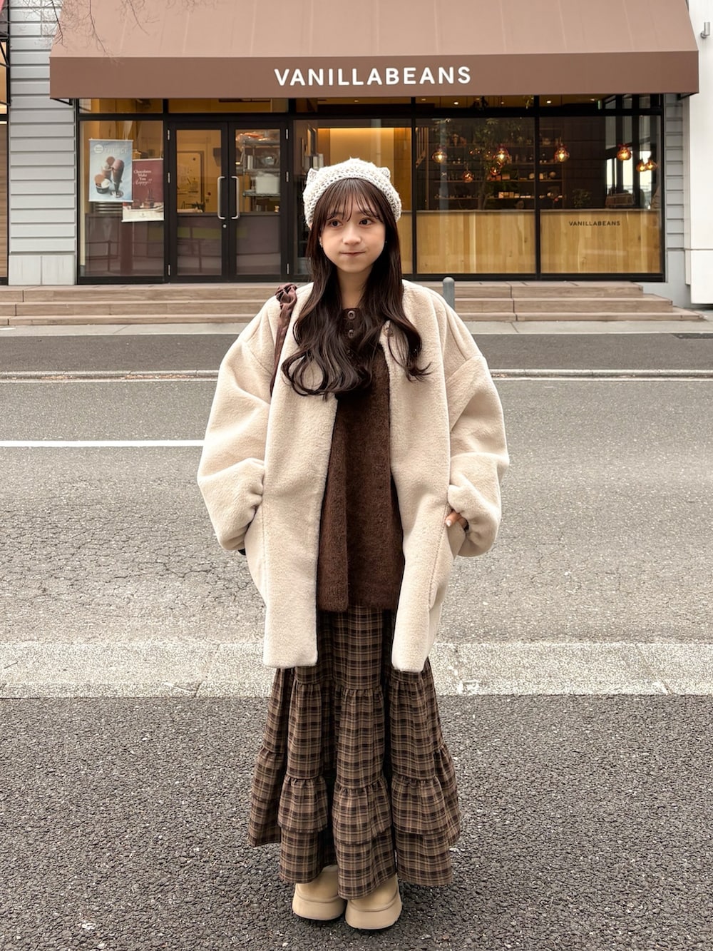 ブラウン系のニット/セーター、ブラウン系のスカート、ホワイト系のその他アウターを着用したレディースの冬コーディネートの2枚目の写真