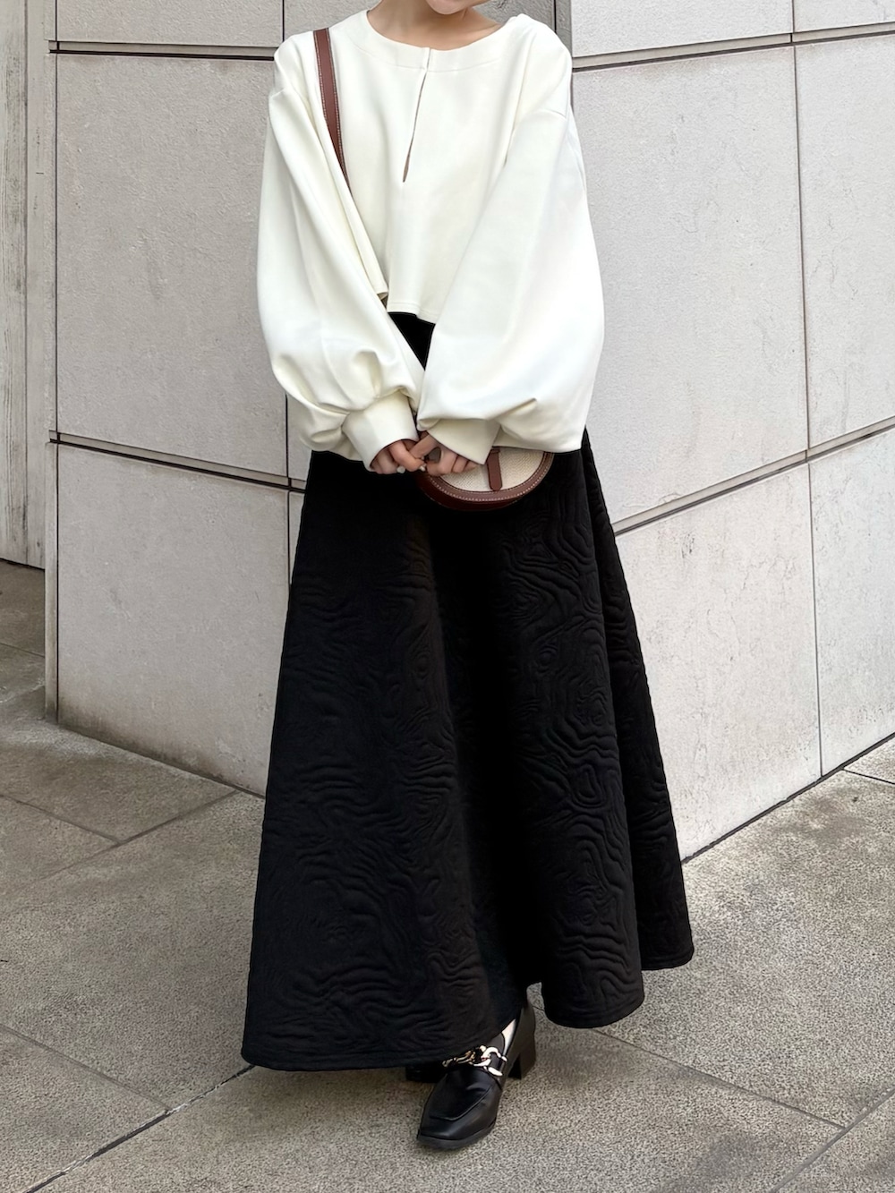 ホワイト系のワンピース、ブラック系のスカート、ブラック系のローファーを着用したレディースの春コーディネートの2枚目の写真