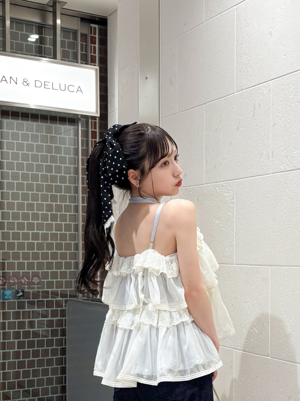 ホワイト系のハンドバッグ、ブルー系のデニムパンツ、ホワイト系のトップスを着用したレディースの夏コーディネートの2枚目の写真