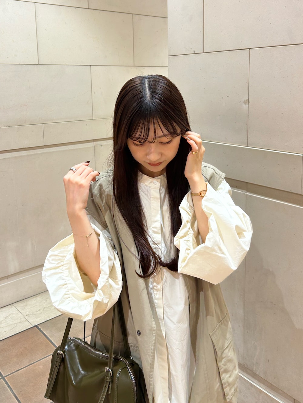 ブラック系のスラックス、ベージュ系のシャツ/ブラウス、グリーン系のトートバッグを着用したレディースの秋コーディネートの4枚目の写真