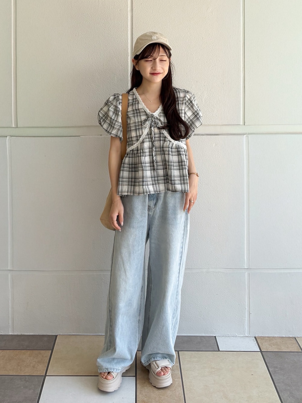 ブラック系のトップス、ベージュ系のショルダーバッグ、ブルー系のデニムパンツを着用したレディースの秋コーディネートの5枚目の写真