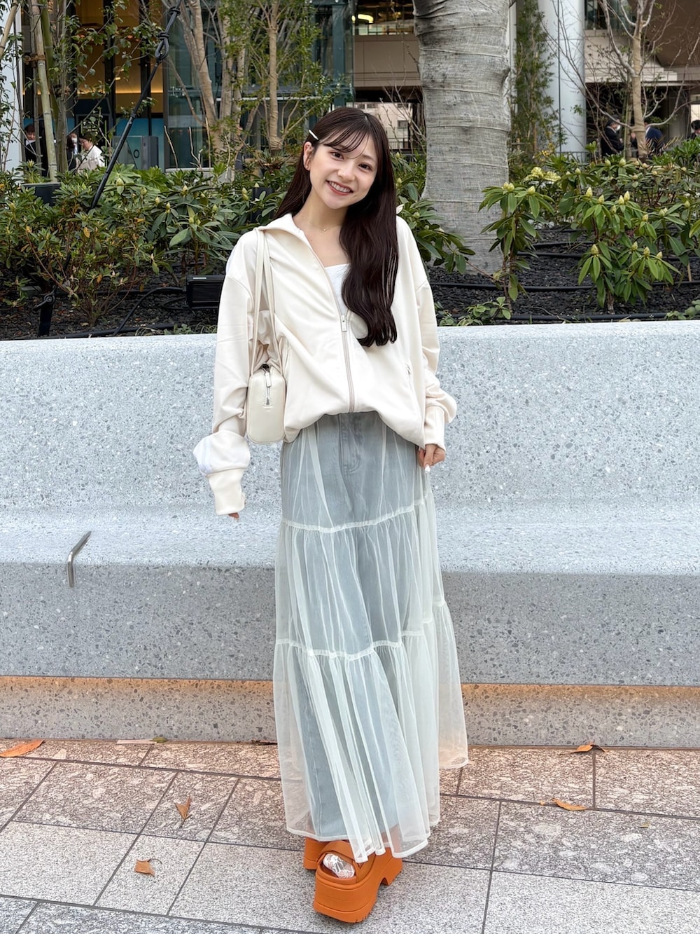 ホワイト系のスカート、オレンジ系のサンダル、ホワイト系のジャージを着用したレディースの春コーディネートの2枚目の写真