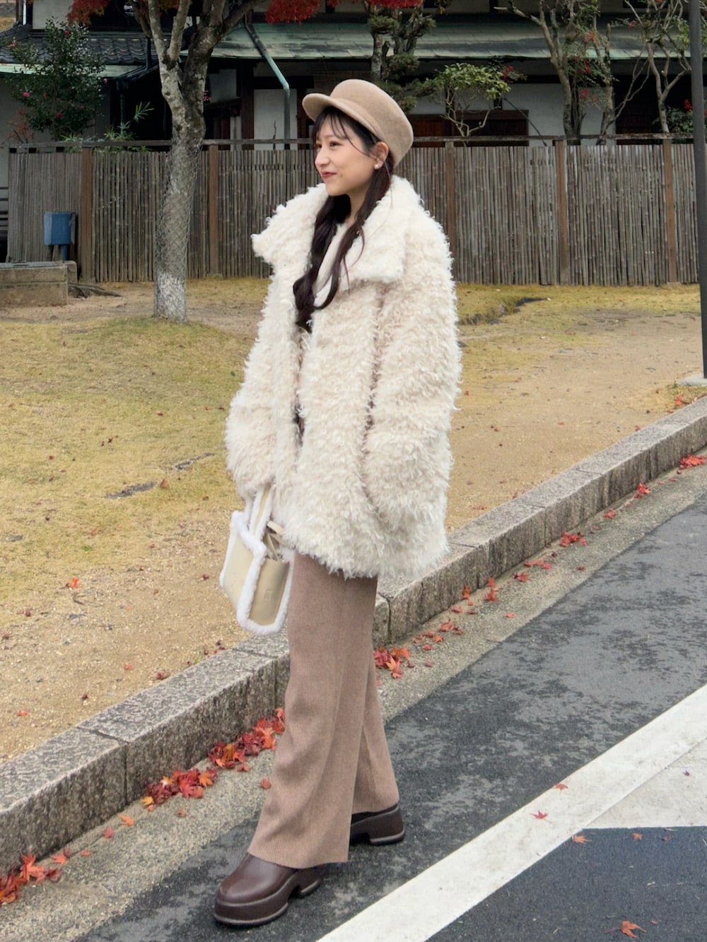 ホワイト系のハンドバッグ、ホワイト系のその他アウター、ブラウン系のブーツを着用したレディースの冬コーディネートの2枚目の写真