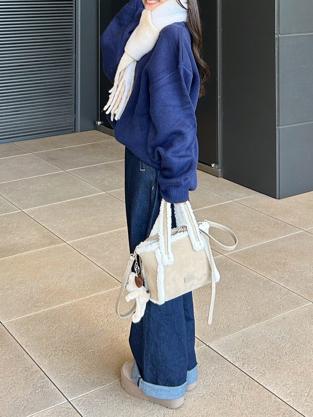 ベージュ系のトートバッグ、ブルー系のデニムパンツ、ベージュ系のブーツを着用したレディースの秋コーディネートの2枚目の写真