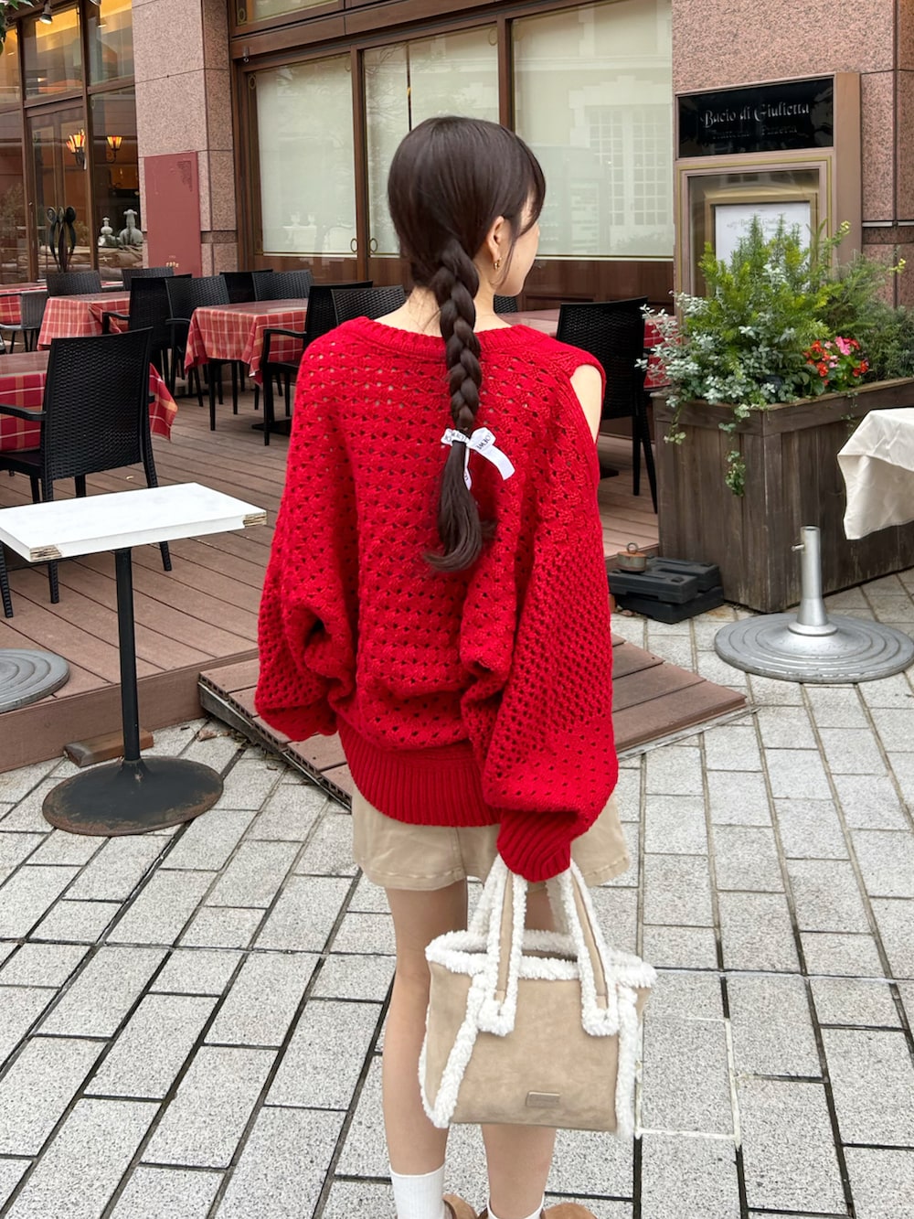 レッド系のニット/セーター、ベージュ系のデニムスカート、ベージュ系のブーツを着用したレディースの秋コーディネートの3枚目の写真