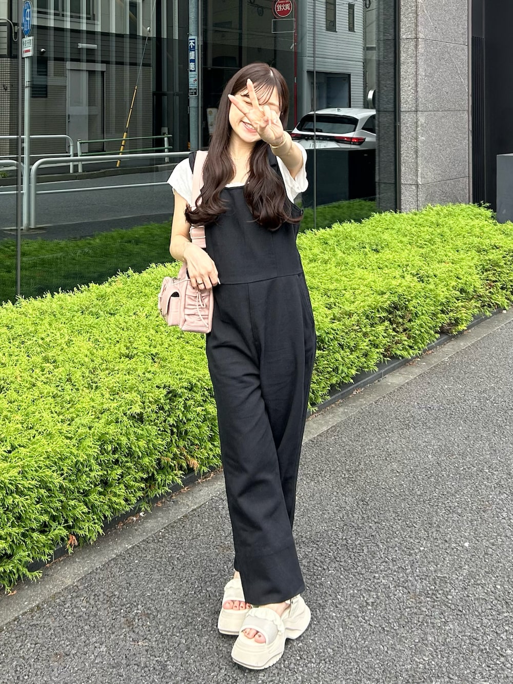 ホワイト系のサンダル、ブラック系のサロペット/オーバーオール、ピンク系のショルダーバッグを着用したレディースの夏コーディネートの2枚目の写真