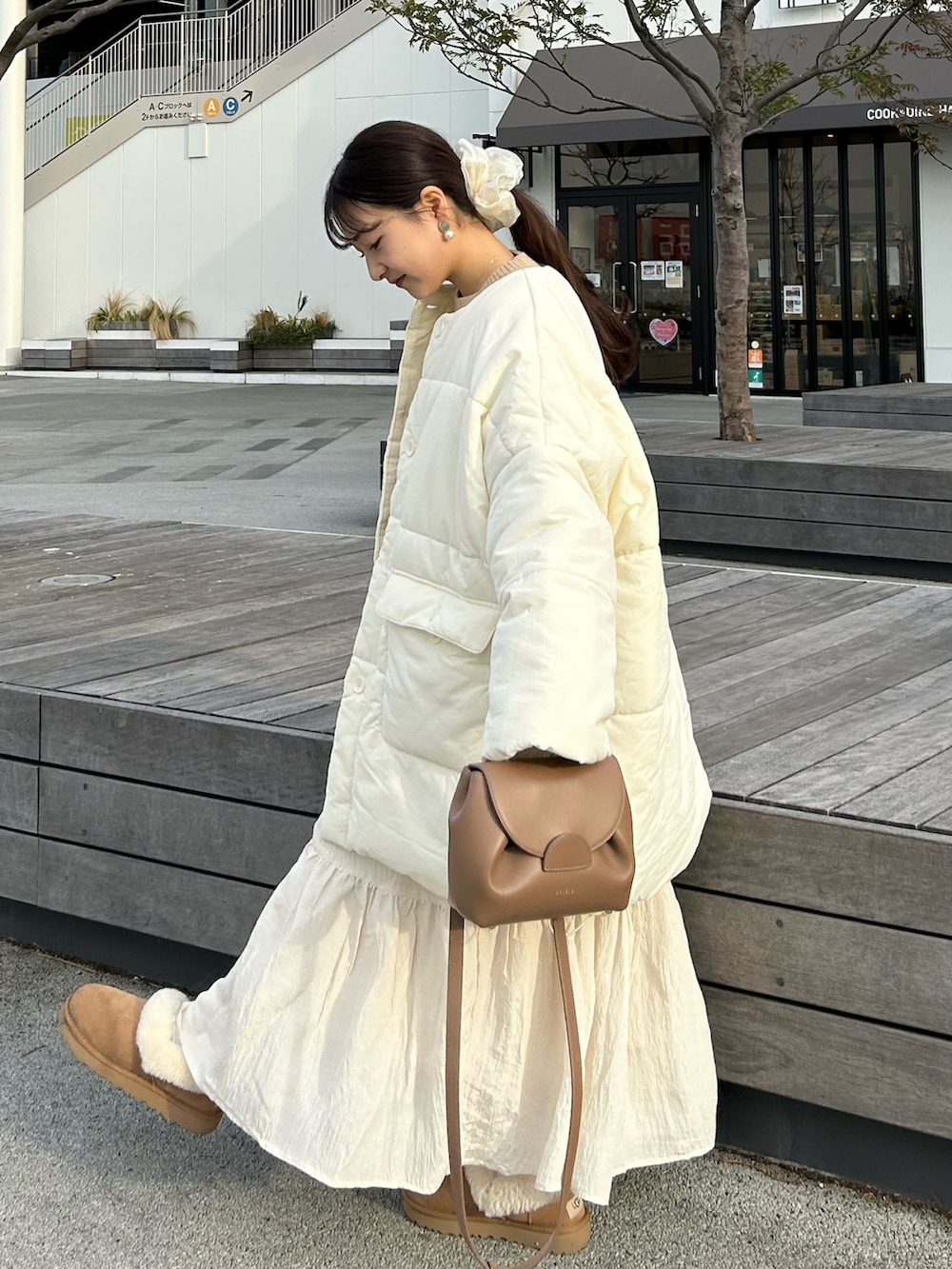 ブラウン系のバッグ、ベージュ系のニット/セーター、ホワイト系のダウンジャケット/コートを着用したレディースの冬コーディネートの2枚目の写真