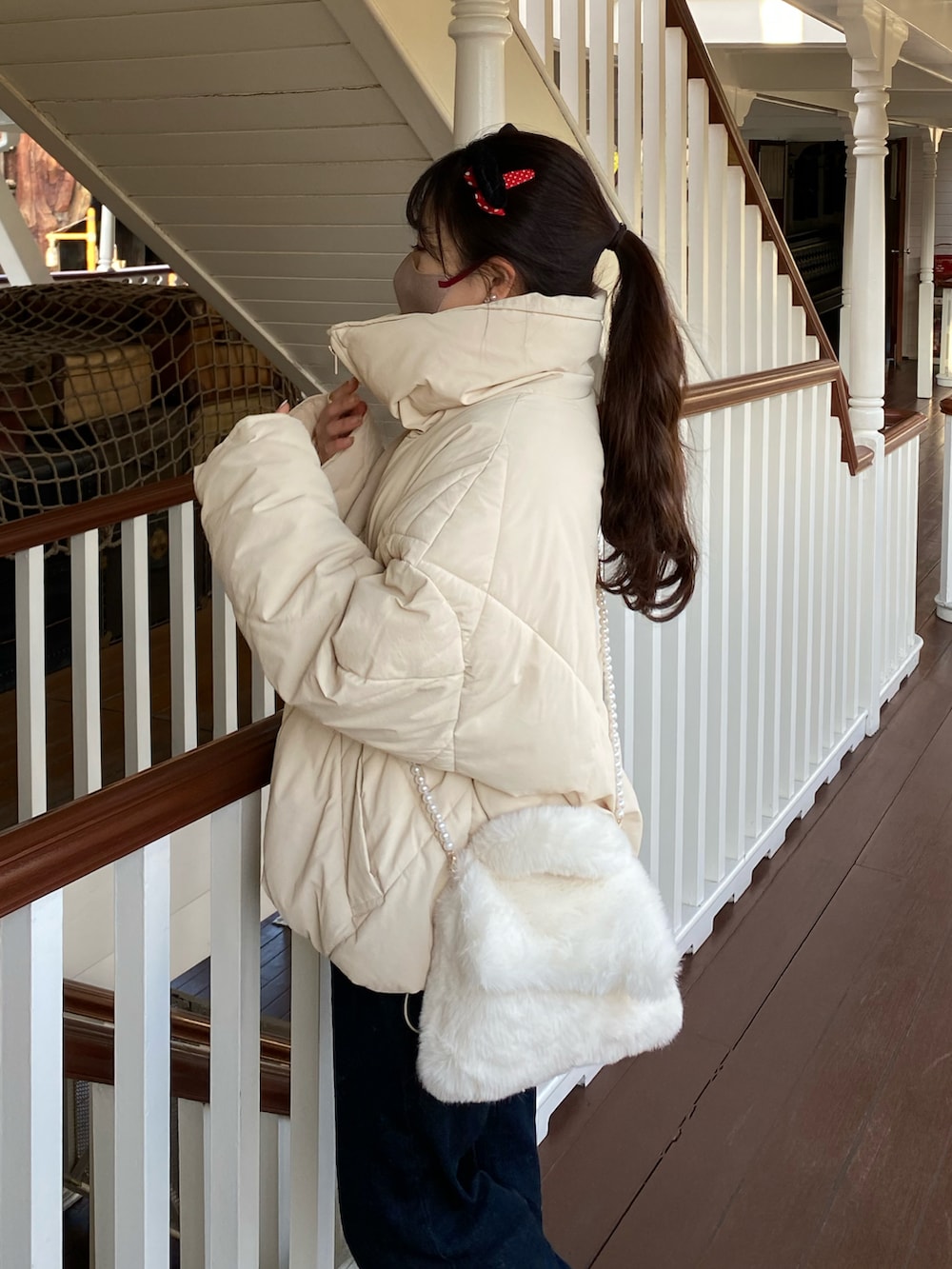 ブルー系のデニムパンツ、ホワイト系のダウンジャケット/コート、ホワイト系のバッグを着用したレディースの冬コーディネートの4枚目の写真