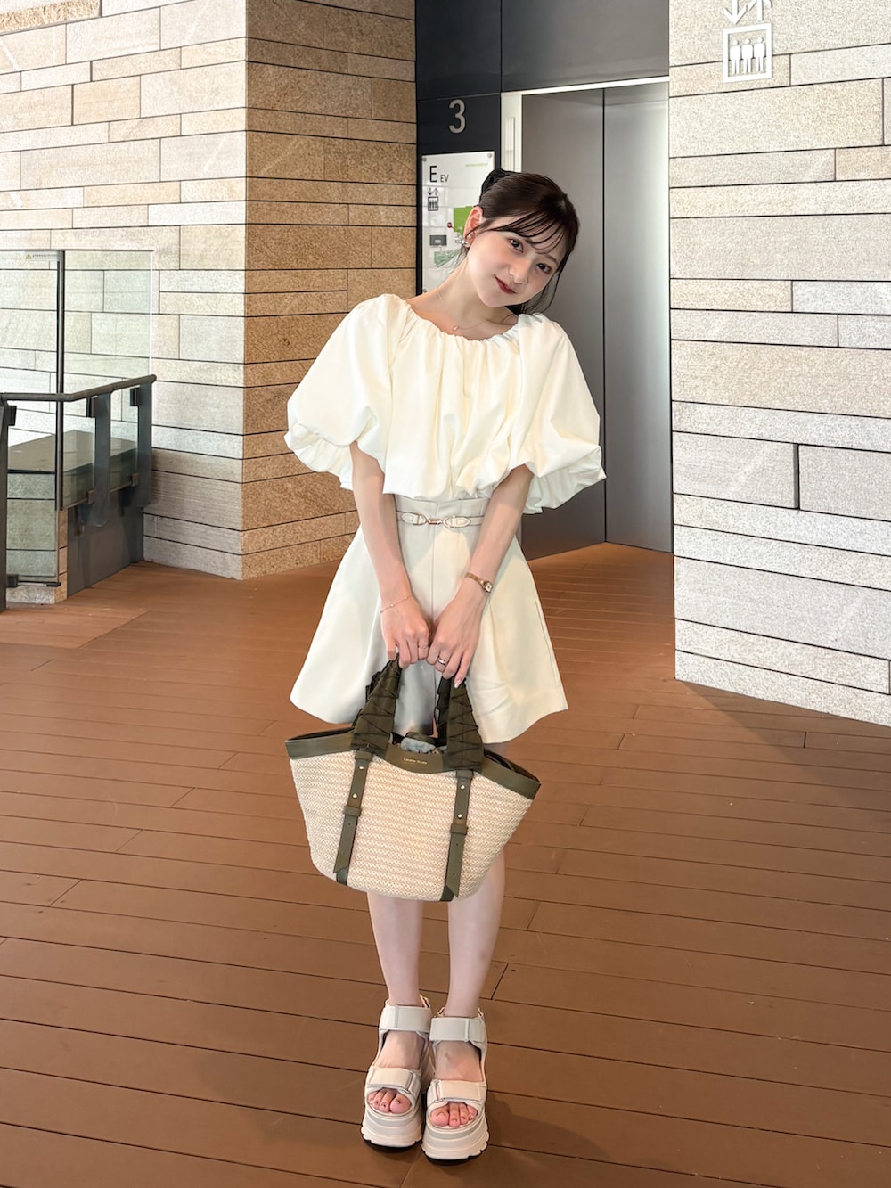 ベージュ系のサンダル、ホワイト系のシャツ/ブラウス、グリーン系のハンドバッグを着用したレディースの夏コーディネートの2枚目の写真