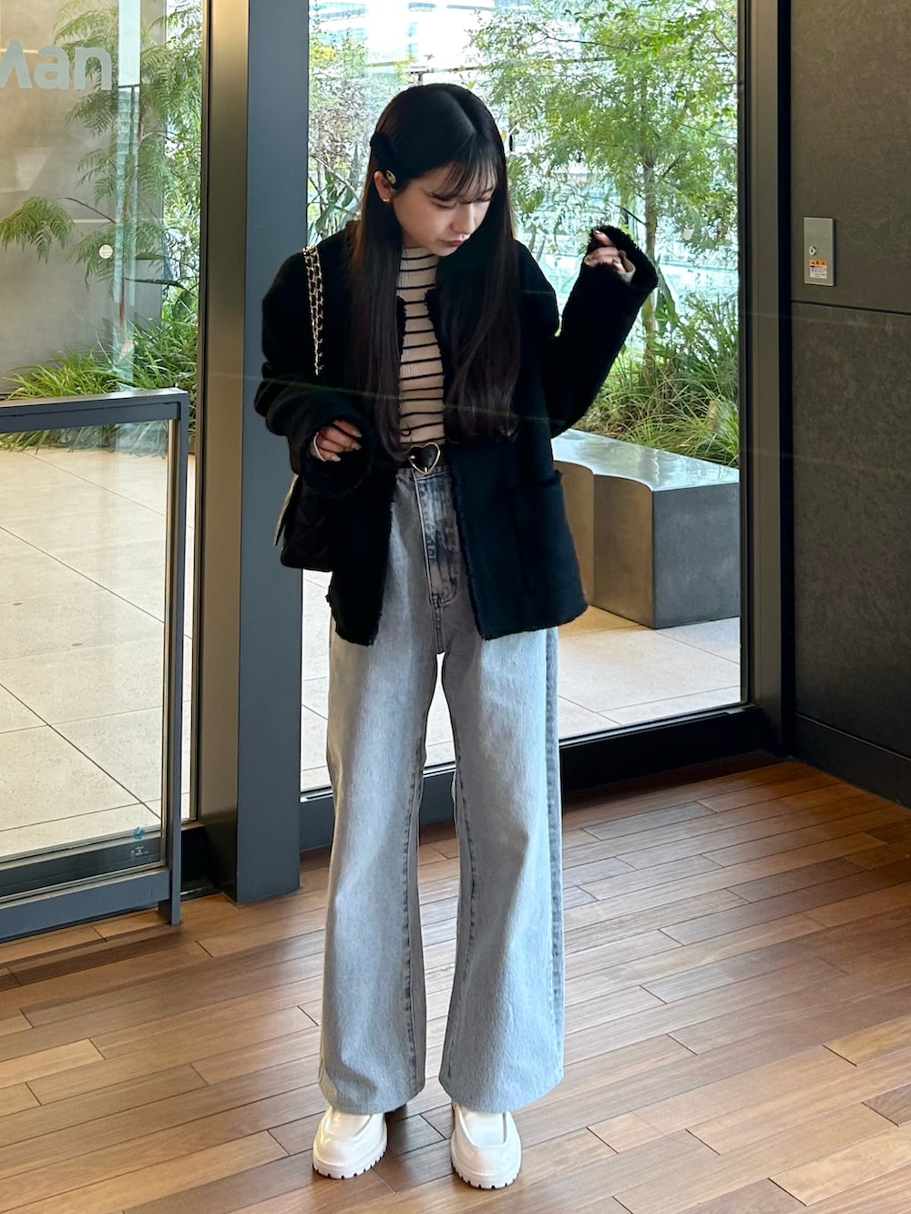 ブルー系のデニムパンツ、ブラック系のジャケット/アウター、ホワイト系のニット/セーターを着用したレディースの春コーディネートの2枚目の写真