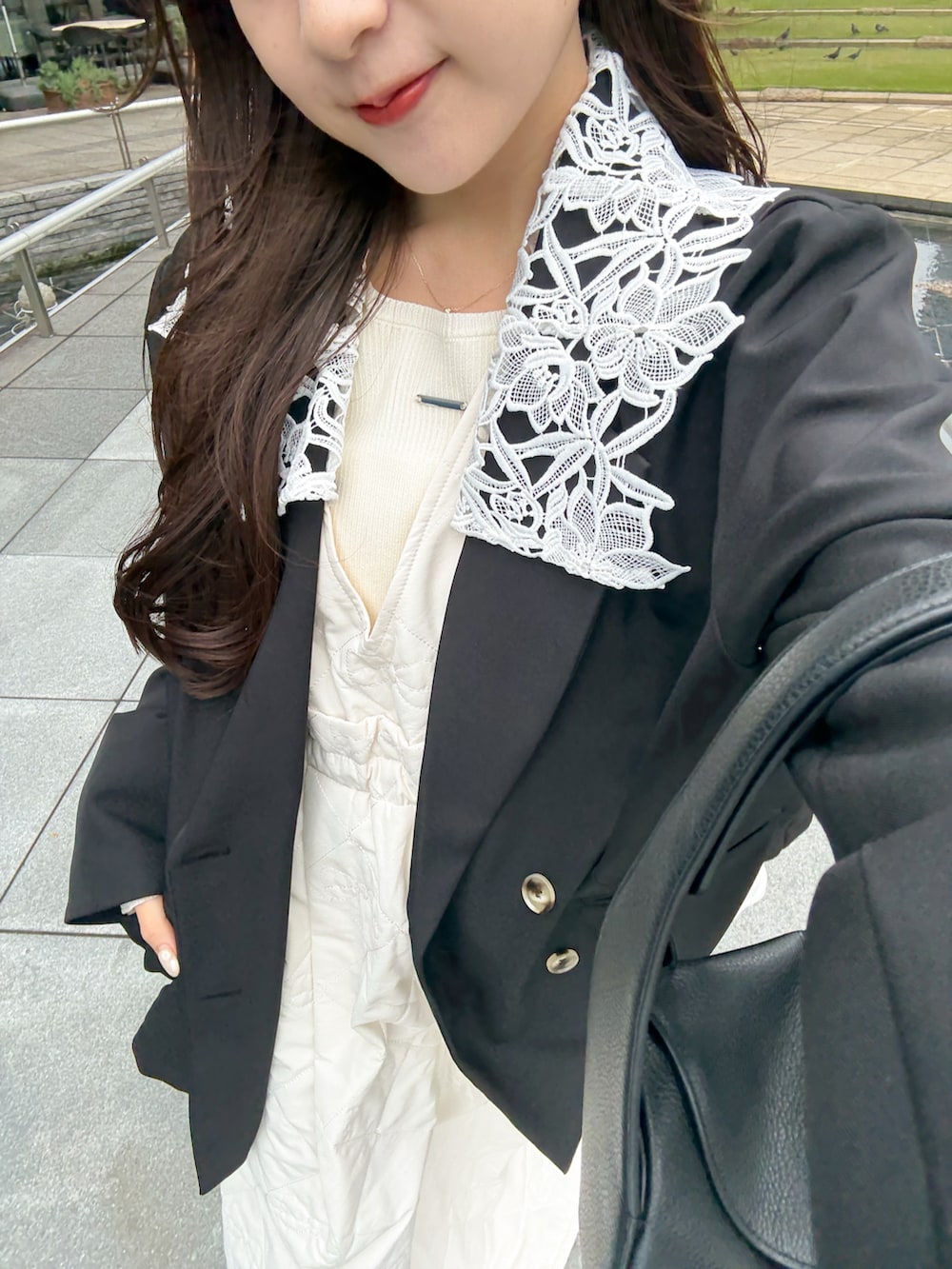 ホワイト系のニット/セーター、ブラック系のテーラードジャケット、ブラック系のブーツを着用したレディースの秋コーディネートの3枚目の写真