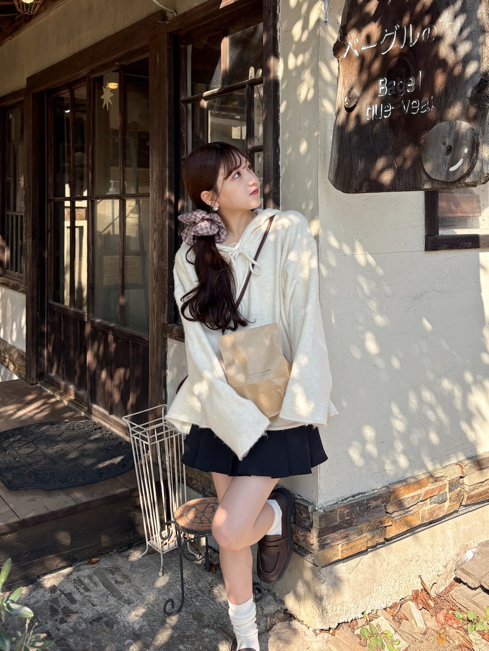 ホワイト系のパーカー、ブラック系のスカート、ブラウン系のローファーを着用したレディースの秋コーディネートの2枚目の写真