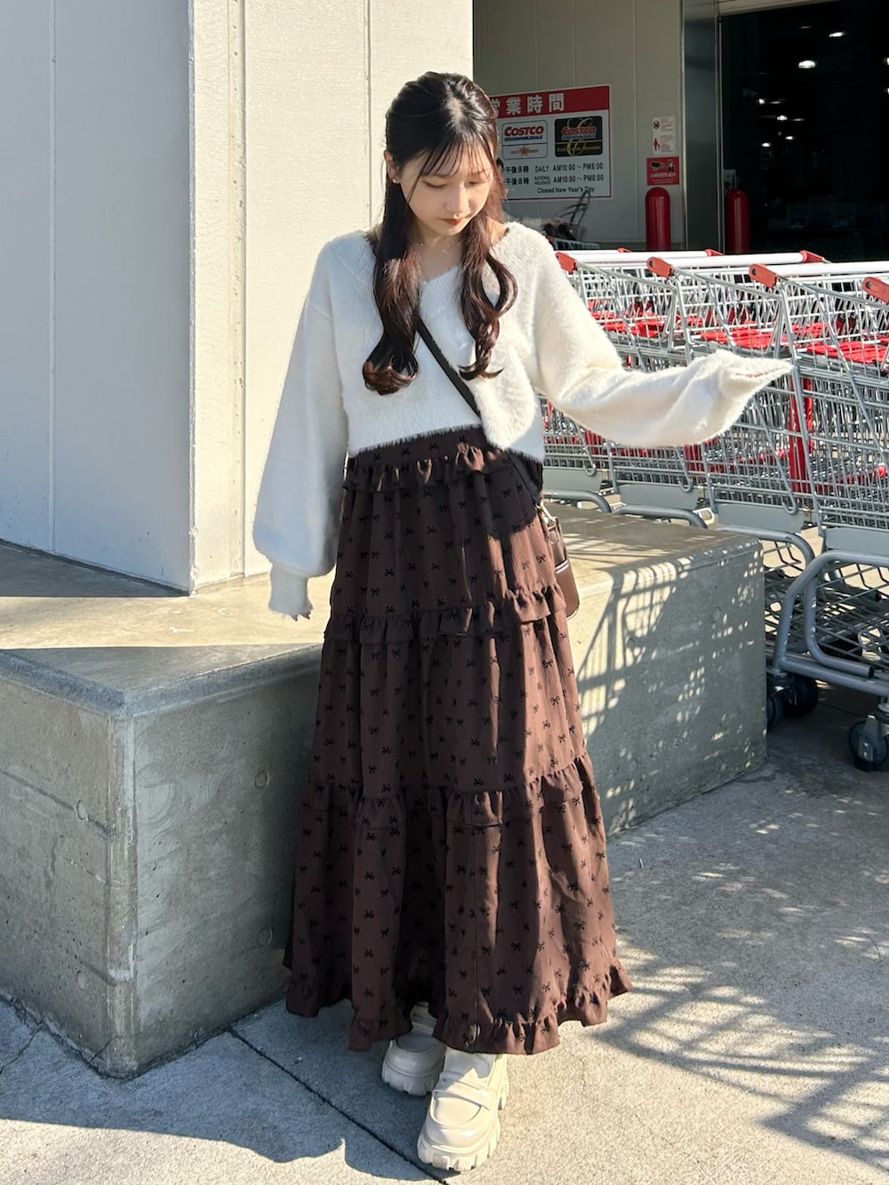 ブラウン系のバッグ、ホワイト系のローファー、ホワイト系のセットアップを着用したレディースの秋コーディネートの2枚目の写真