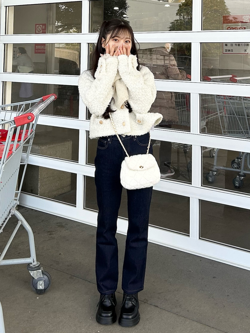 ブルー系のデニムパンツ、ホワイト系のショルダーバッグ、ホワイト系のニット/セーターを着用したレディースの冬コーディネートの5枚目の写真