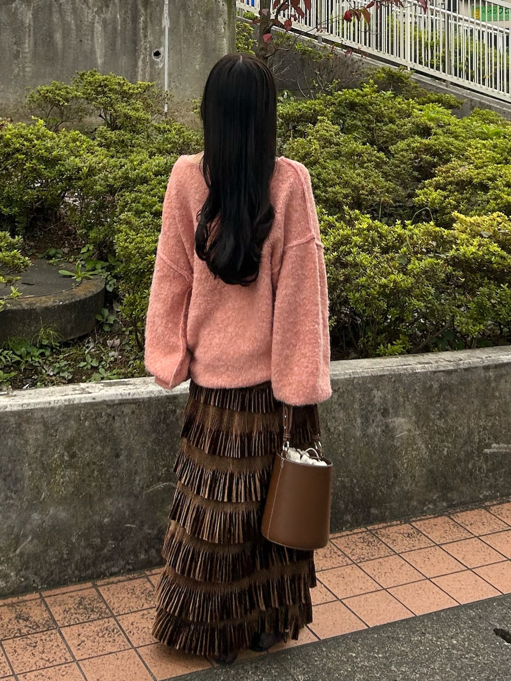 ピンク系のニット/セーター、ブラウン系のスカート、ブラウン系のハンドバッグを着用したレディースの秋コーディネートの3枚目の写真