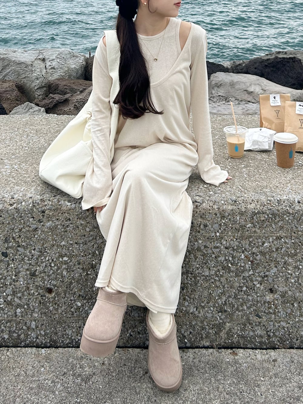 ベージュ系のワンピース、ホワイト系のショルダーバッグ、ベージュ系のブーツを着用したレディースの秋コーディネートの2枚目の写真